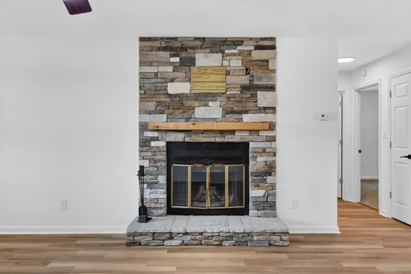 a view of an empty room with wooden floor and a fireplace