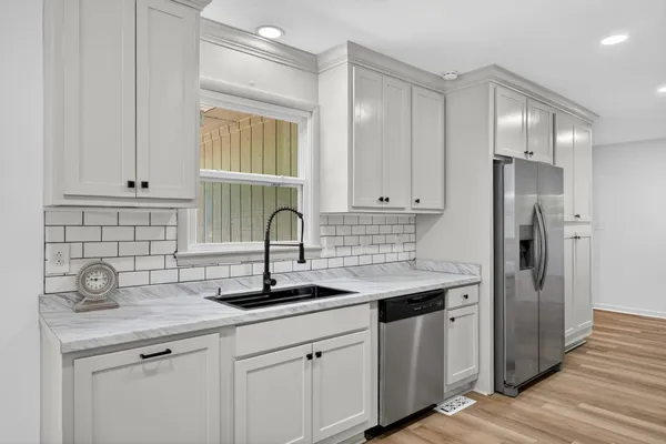 a kitchen with stainless steel appliances granite countertop a sink a refrigerator and window
