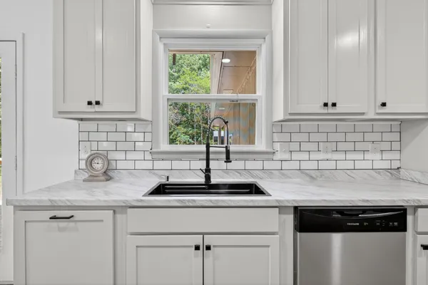 a kitchen with granite countertop white cabinets and a window