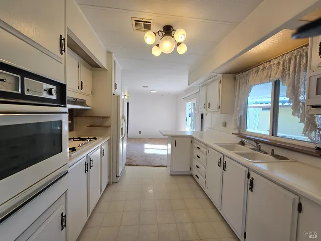 a large kitchen with stainless steel appliances a stove sink and cabinets