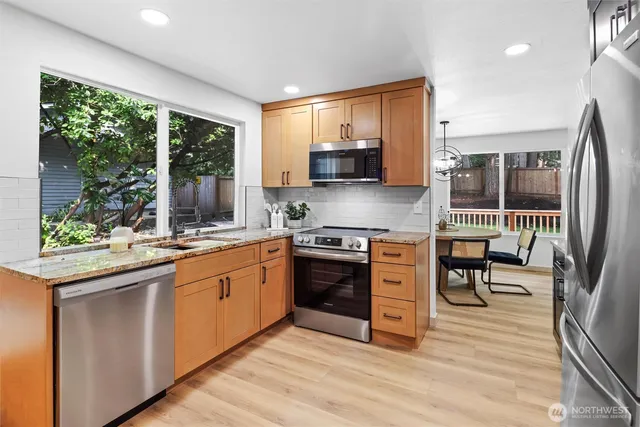 a kitchen with stainless steel appliances granite countertop a stove top oven a sink and a granite counter tops with large windows