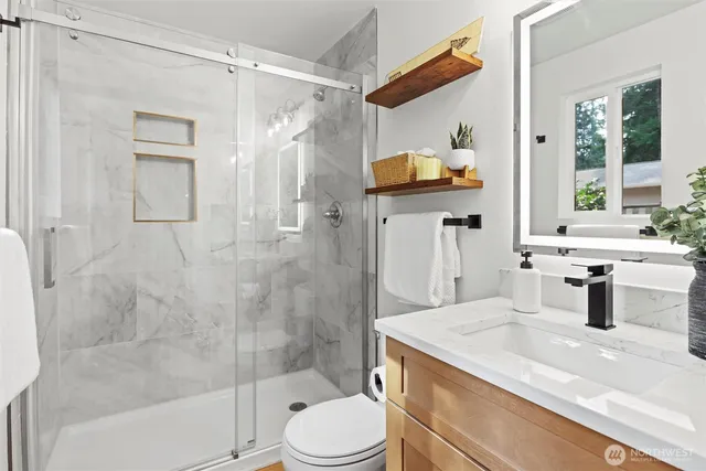 a bathroom with a granite countertop sink a toilet a mirror and shower