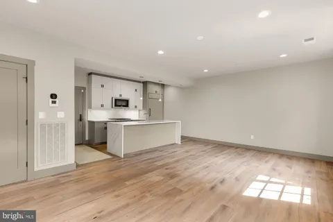 a large white kitchen with kitchen island a sink dishwasher a stove and a refrigerator with wooden floor