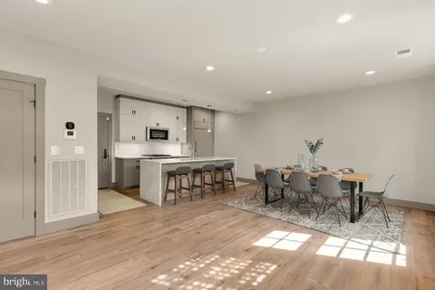 a living room with stainless steel appliances furniture a dining table and kitchen view