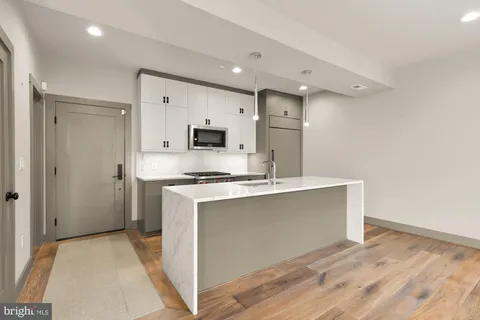 a kitchen with kitchen island a sink stainless steel appliances and white cabinets