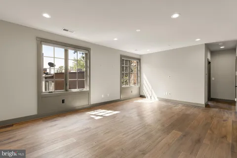 a view of empty room with wooden floor and fan