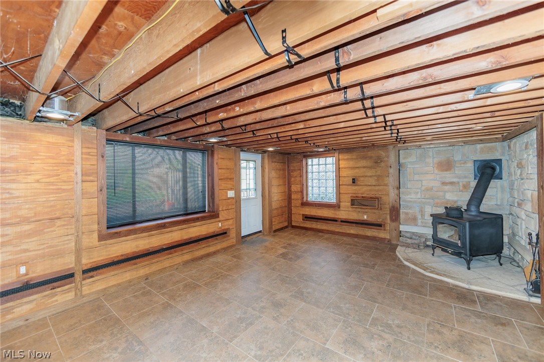 38565 Sugar Ridge Road North Ridgeville, OH 44039 - Photo 38 of 49 Basement with wood walls, dark tile flooring, and a wood stove
