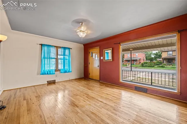 an empty room with wooden floor and windows