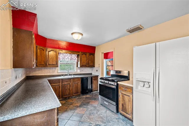 a kitchen with stainless steel appliances granite countertop a stove a sink and a refrigerator