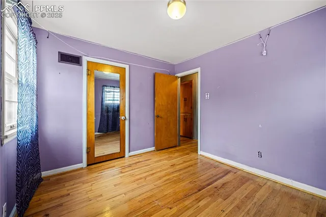 a view of an empty room with wooden floor and windows