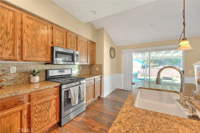 a kitchen with stainless steel appliances granite countertop a stove a sink and a microwave
