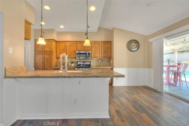 a kitchen with stainless steel appliances granite countertop a sink a stove and a wooden floors