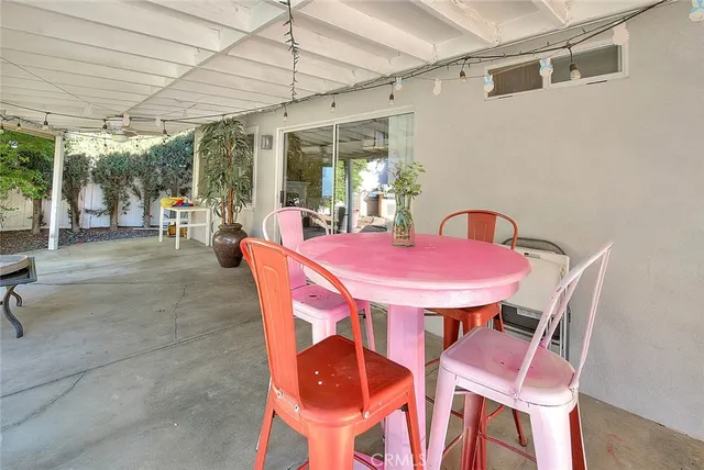 a view of a patio with couches table and chairs under an umbrella
