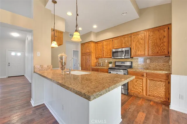 a kitchen with granite countertop a sink a counter space appliances and cabinets