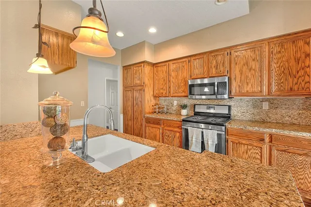 a kitchen with stainless steel appliances granite countertop a sink a stove a microwave a dining table and chairs with wooden floor