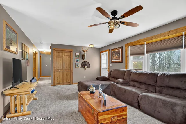 a living room with furniture ceiling fan and a large window