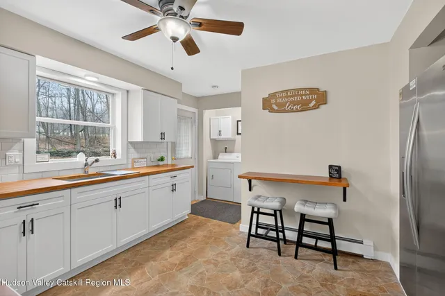 a large white kitchen with a refrigerator a sink dishwasher a dining table and chairs with wooden floor