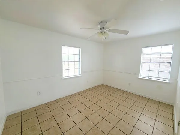 an empty room with windows and fan
