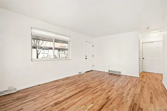 a view of empty room with wooden floor and fan