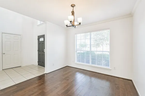 an empty room with wooden floor chandelier and windows