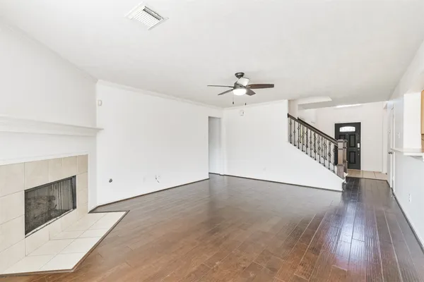 a view of an empty room with wooden floor and a fireplace