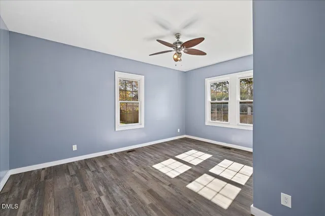 a view of empty room with wooden floor and fan