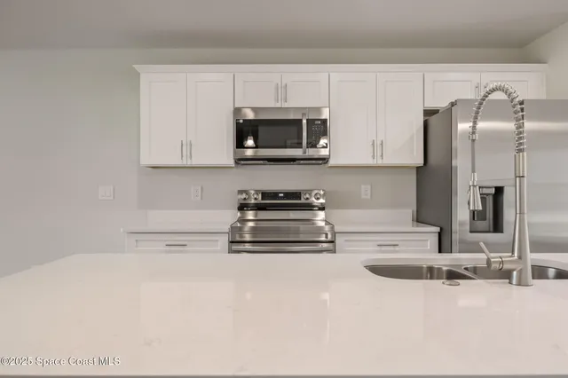 a kitchen with stainless steel appliances granite countertop a sink a stove and a refrigerator