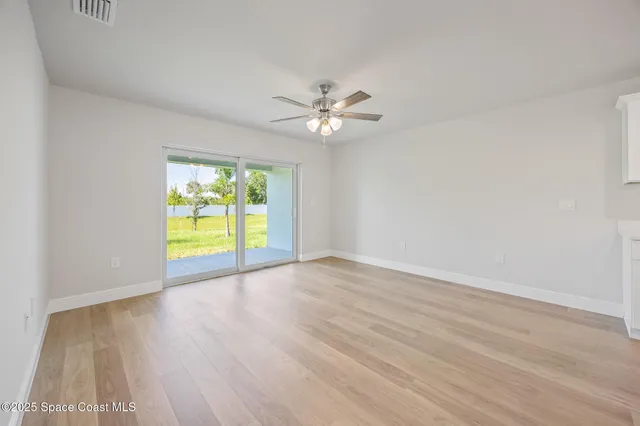 a view of an empty room with a window and wooden floor