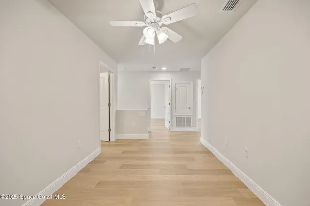 an empty room with wooden floor and ceiling fan