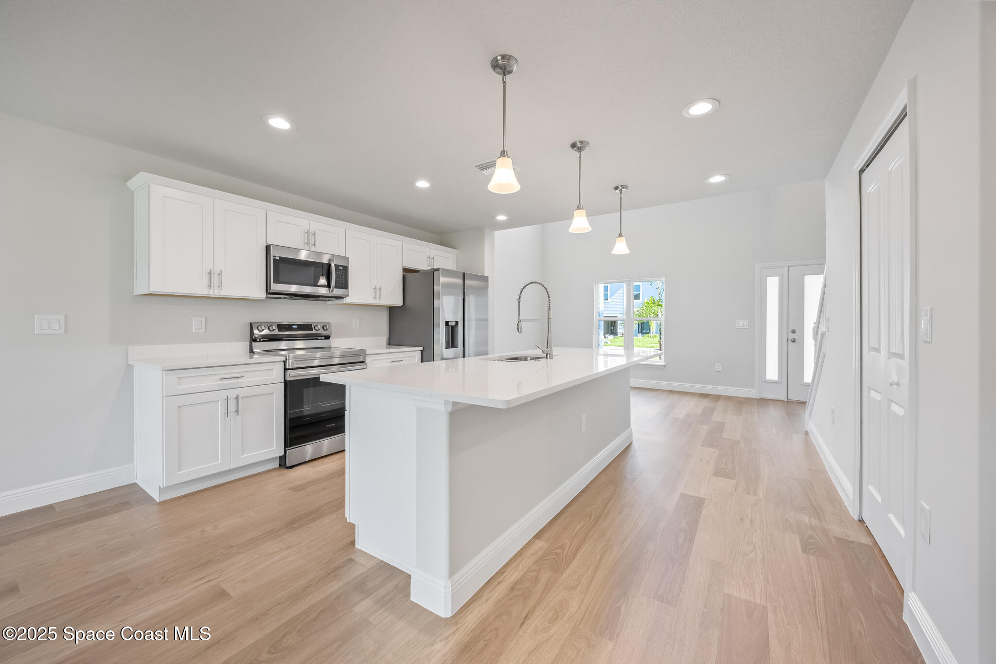 168 Hidden Wds Place Melbourne, FL 32901 - Photo 9 of 31 a large white kitchen with kitchen island a sink dishwasher a stove a refrigerator and white cabinets with wooden floor