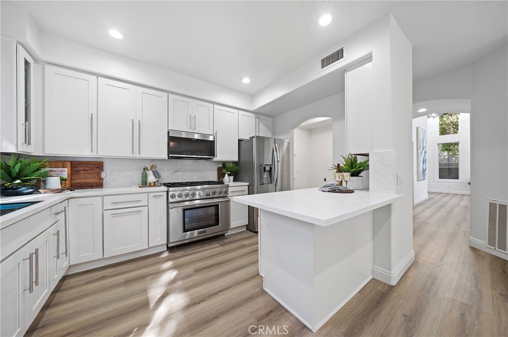 18 Broadleaf Irvine, CA 92612 - Photo 14 of 52 a kitchen that has a lot of white cabinets and wooden floor