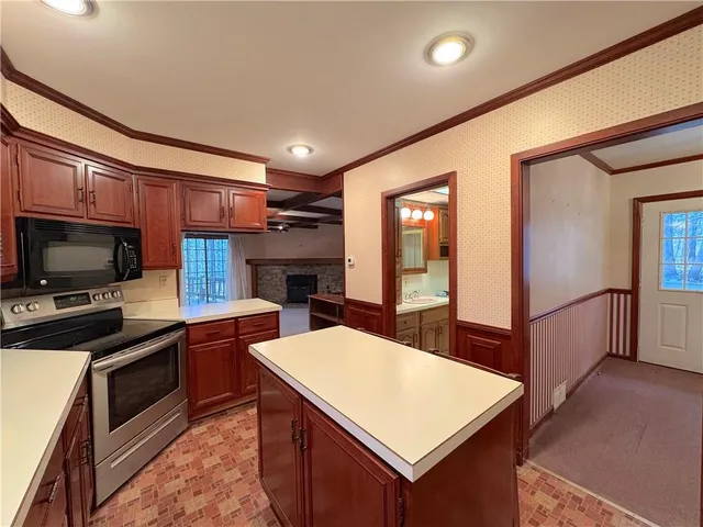 a kitchen with stainless steel appliances kitchen island granite countertop a refrigerator a stove top oven a sink dishwasher and white cabinets with wooden floor