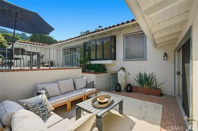 a view of a patio with couches table and chairs under an umbrella