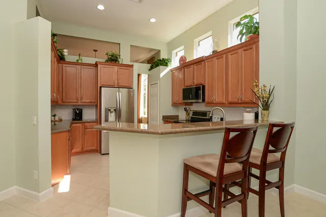 a kitchen with stainless steel appliances granite countertop a refrigerator a stove and a sink with wooden cabinets