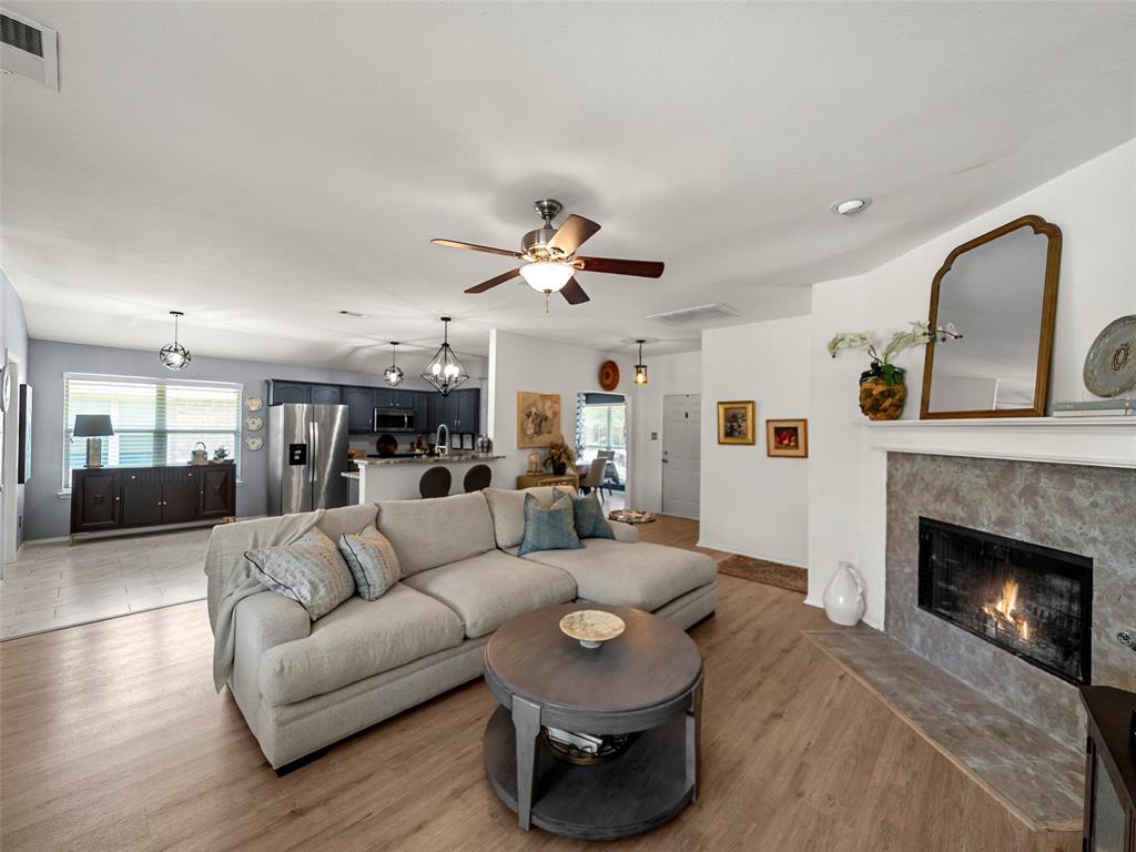 204 Arbor Ridge Drive Allen, TX 75002 - Photo 26 of 36 Living area featuring wood-finish flooring, a fireplace with a stone surround, and an open concept layout