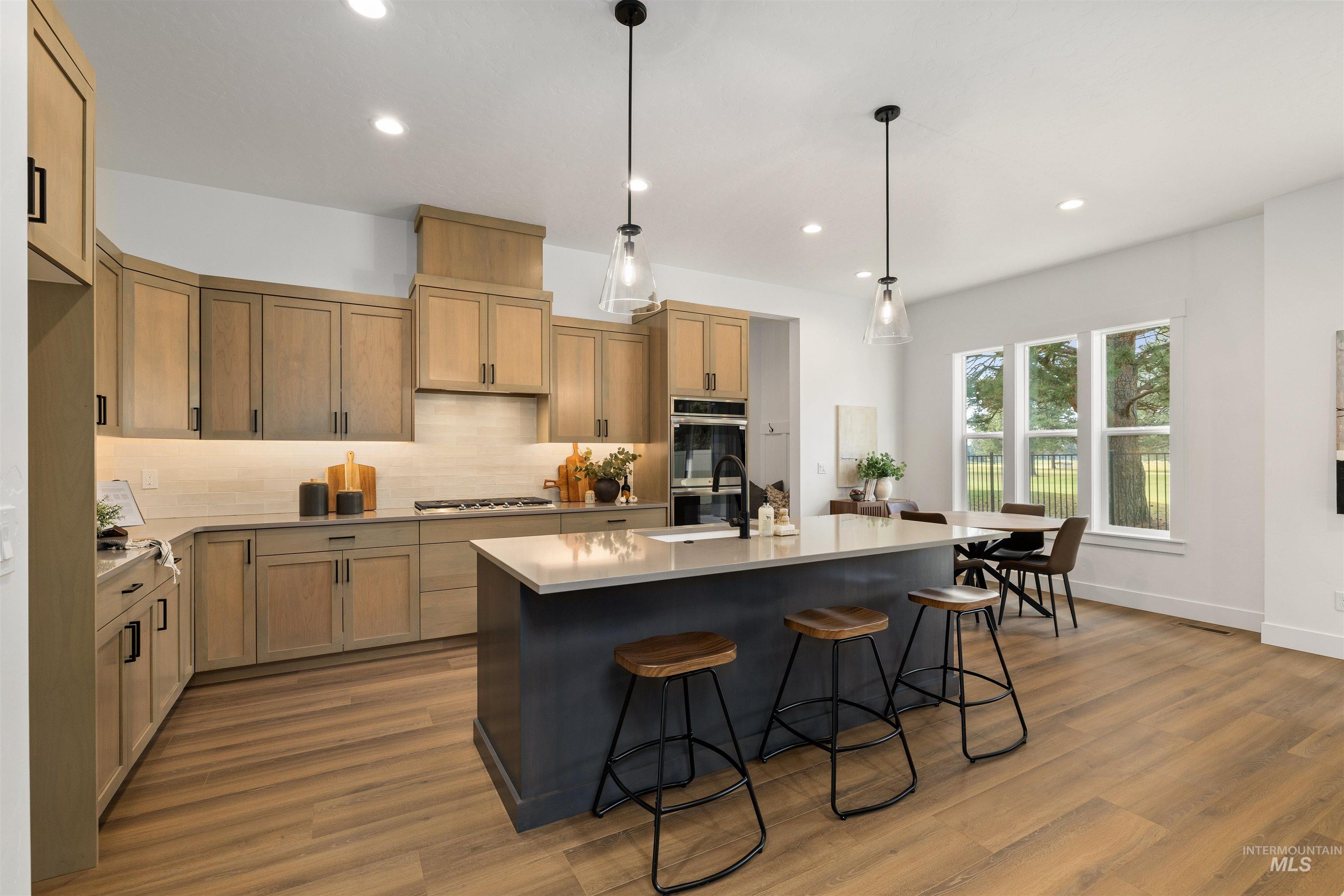 611 North Hiltonhead Way Eagle, ID 83616 - Photo 11 of 37 Kitchen featuring a breakfast bar, pendant lighting, decorative backsplash, a kitchen island with sink, and recessed lighting. Photo Similar.