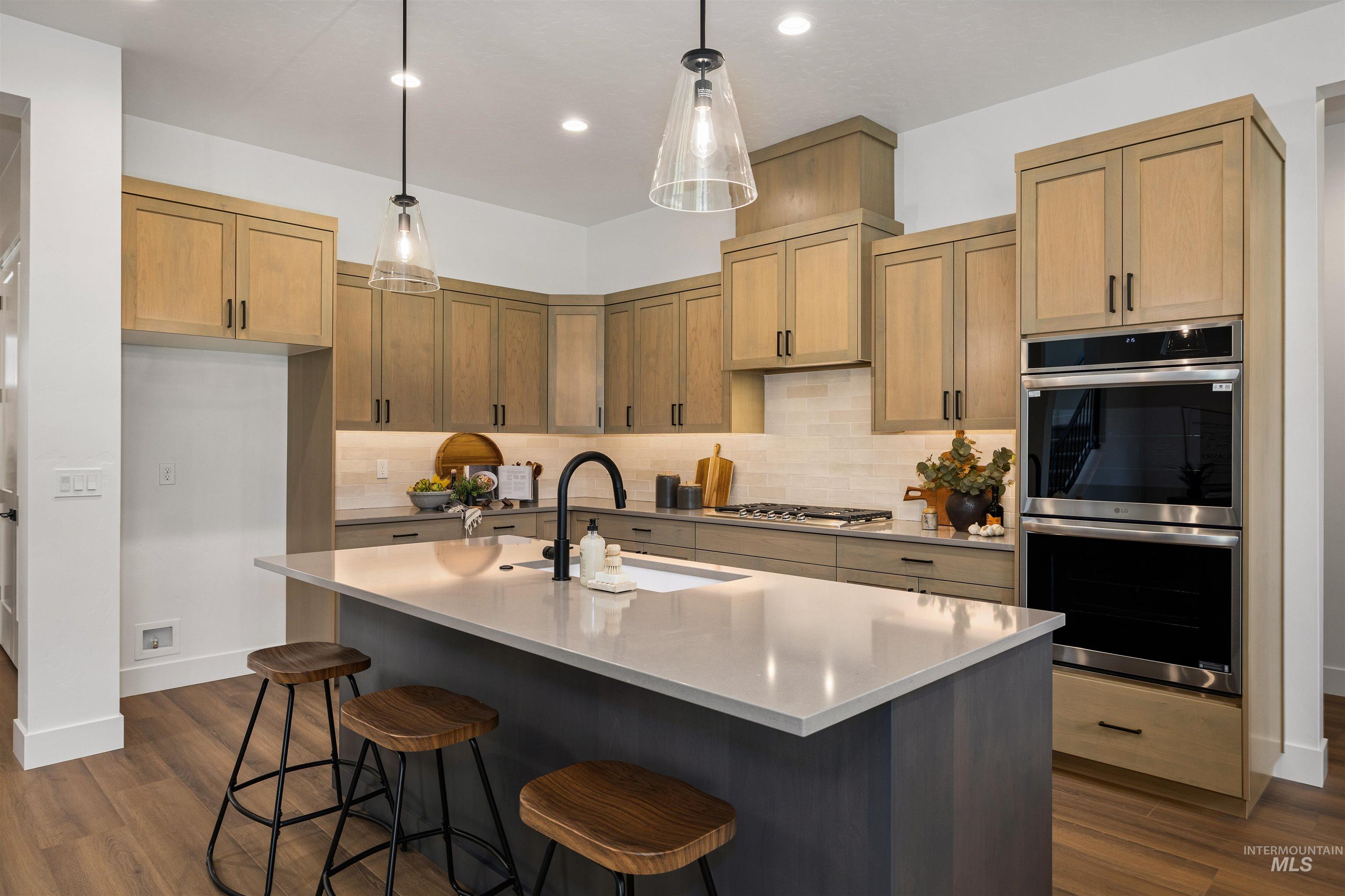 611 North Hiltonhead Way Eagle, ID 83616 - Photo 12 of 37 Kitchen with pendant lighting, an island with sink, appliances with stainless steel finishes, dark wood-style floors, and a kitchen breakfast bar