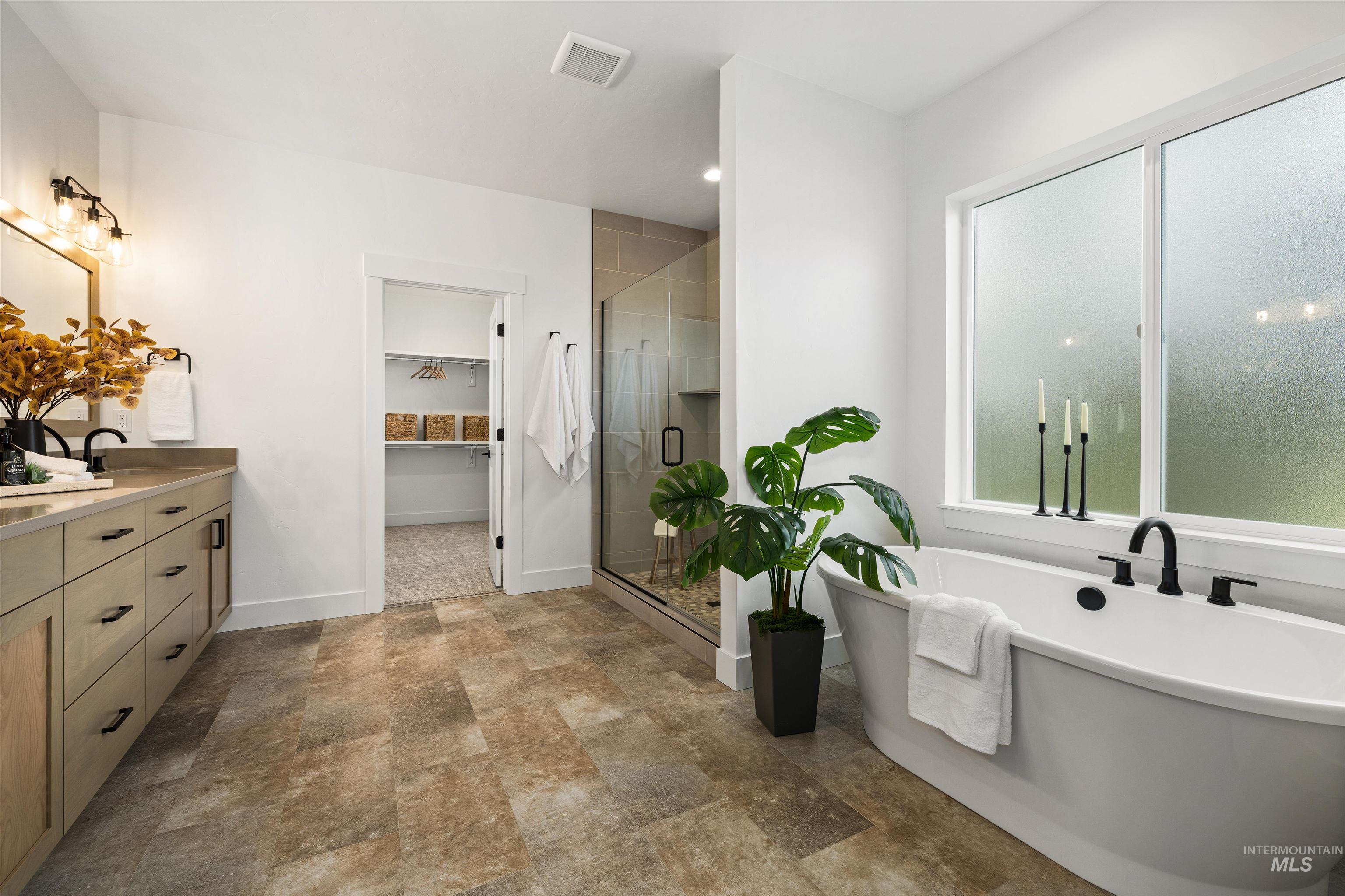 611 North Hiltonhead Way Eagle, ID 83616 - Photo 24 of 37 Full bath with a walk in closet, a shower stall, a freestanding tub, vanity, and stone finish flooring. Photo Similar.