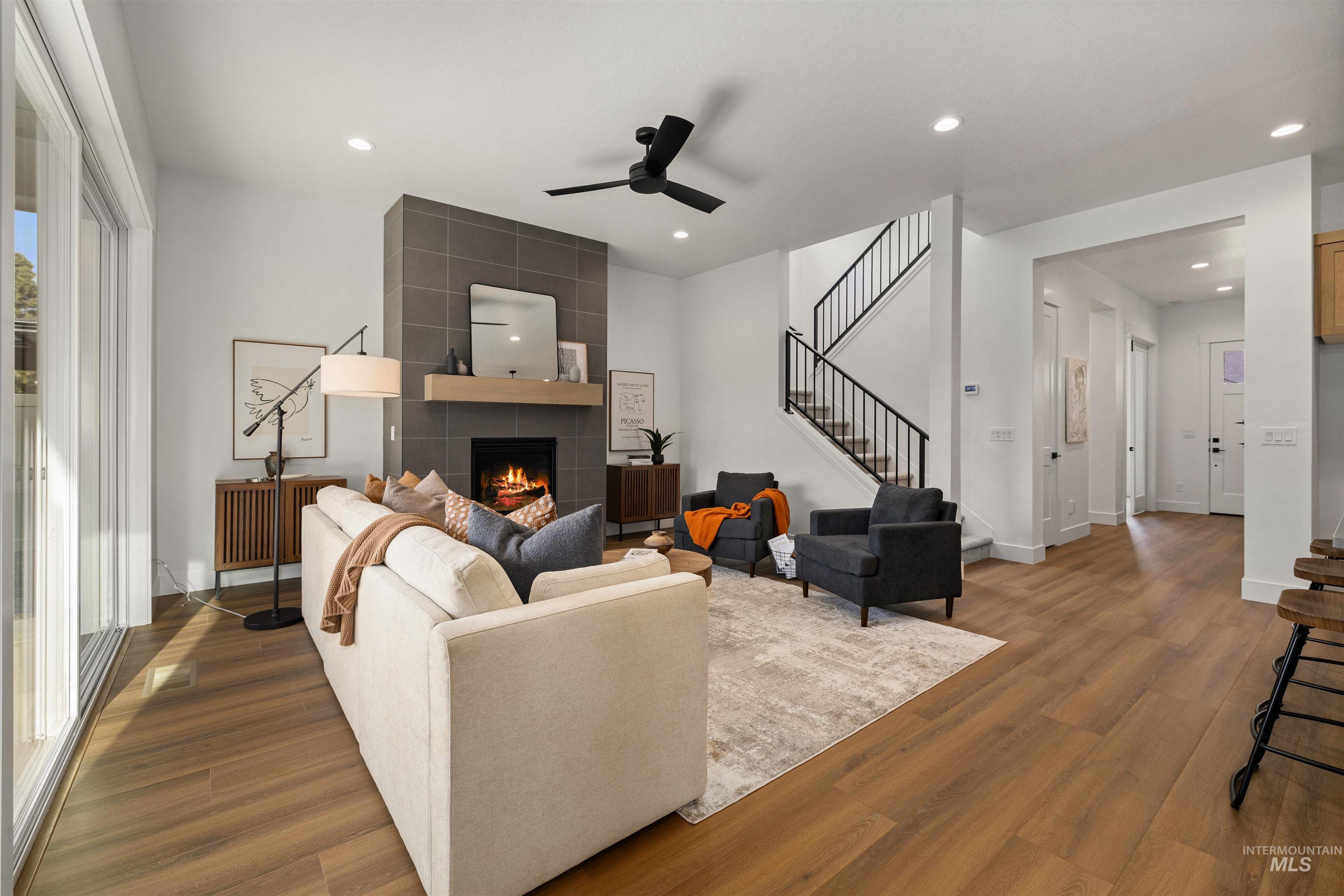 611 North Hiltonhead Way Eagle, ID 83616 - Photo 6 of 37 Living area featuring stairs, dark wood-style floors, a tiled fireplace, a ceiling fan, and recessed lighting. Photo Similar.