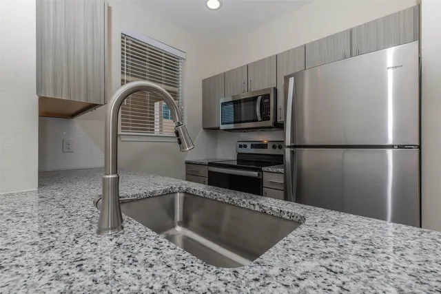 a kitchen with granite countertop a refrigerator and a sink