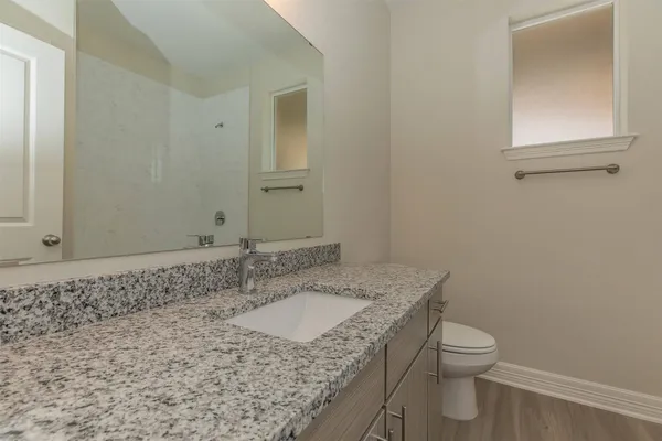 a bathroom with a granite countertop sink a toilet and a mirror