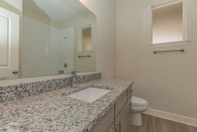 a bathroom with a granite countertop sink a toilet and a mirror