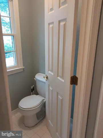 a white toilet sitting next to a window in a bathroom