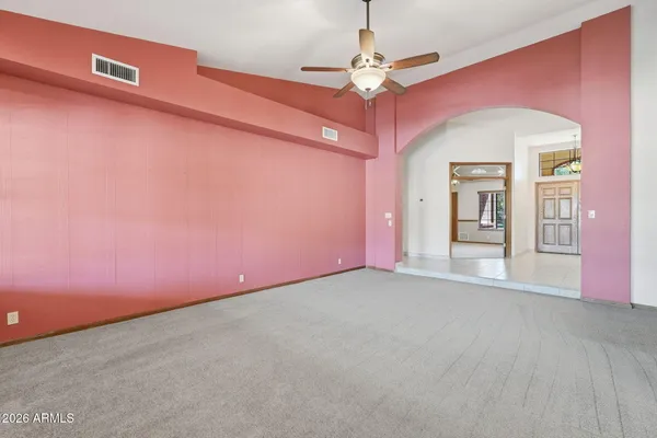 an empty room with chandelier fan and windows