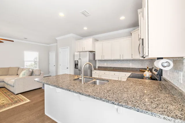 a kitchen with granite countertop a sink a stove and cabinets