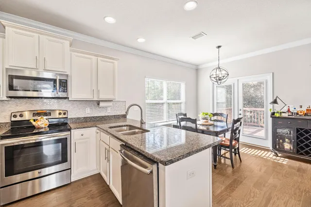 a kitchen with granite countertop stainless steel appliances a stove a sink a oven a dining table and chairs