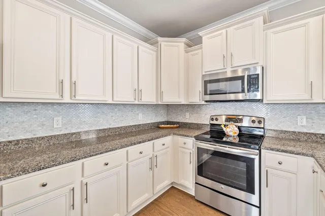 a kitchen with granite countertop white cabinets and stainless steel appliances