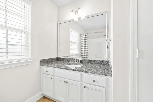 a bathroom with a granite countertop sink and a mirror