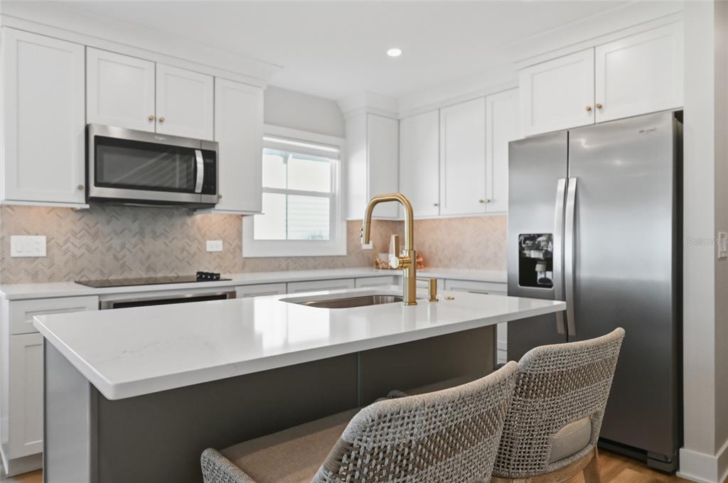 380 Gulf Boulevard, Unit 1 Boca Grande, FL 33921 - Photo 17 of 35 a kitchen with stainless steel appliances granite countertop a sink a stove a refrigerator cabinets and chairs