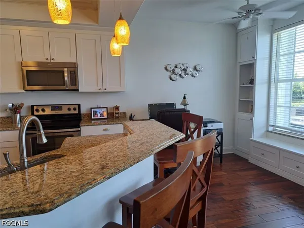 a kitchen with granite countertop a stove a sink and a microwave